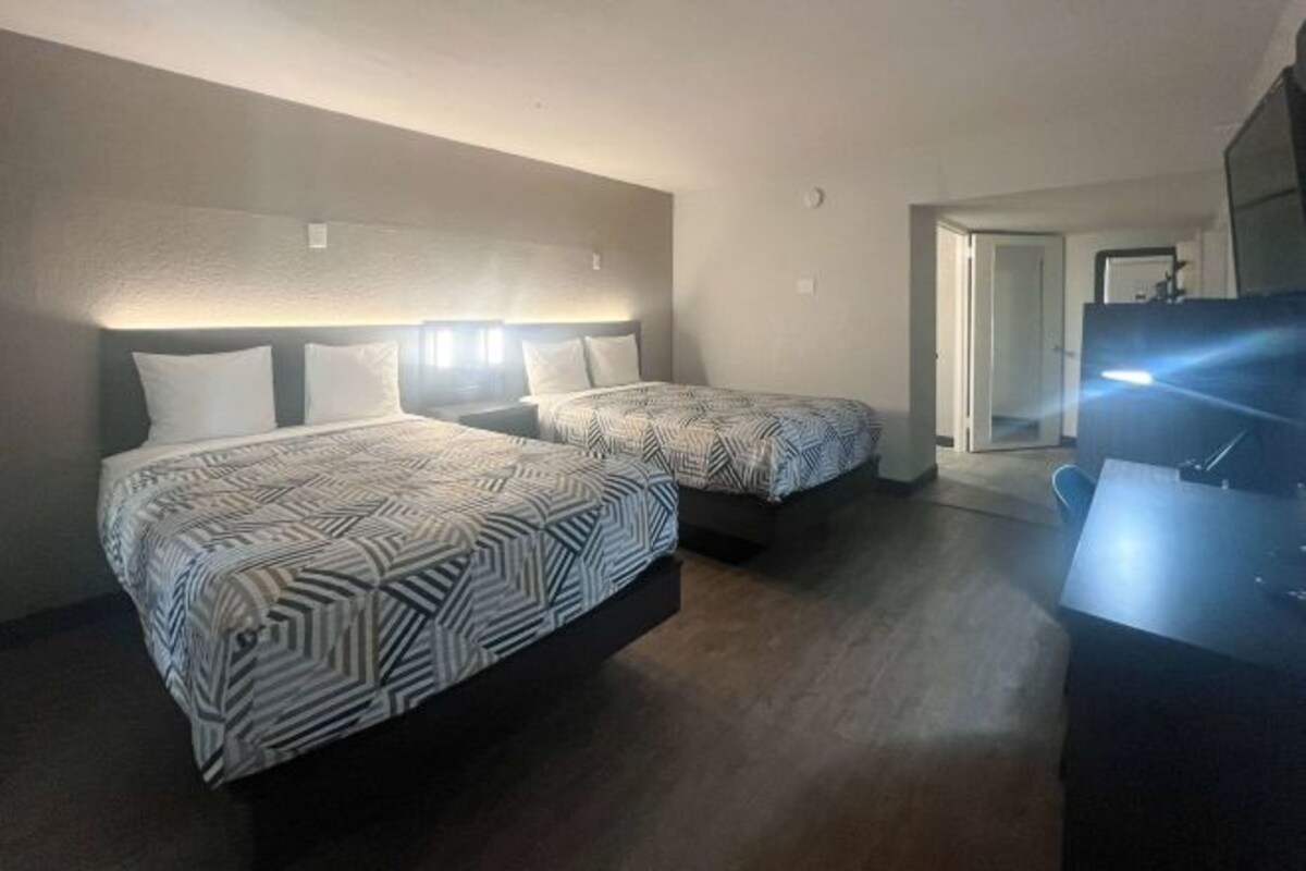Ett hotellrum med två sängar, ett skrivbord och en tv.