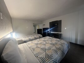 A hotel room with two beds, a desk, a TV, and a mirror.