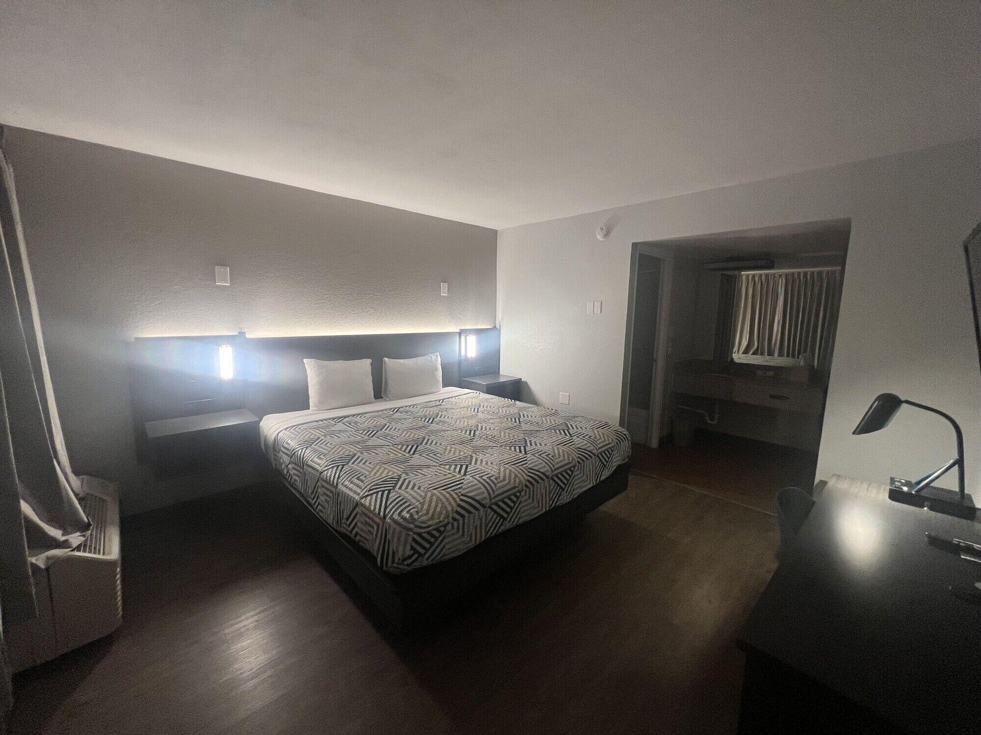 A hotel room with a large bed, bedside tables, a desk, and a chair.