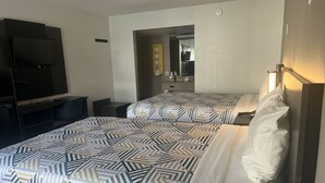 Habitación de hotel con dos camas, televisión, escritorio y espejo.