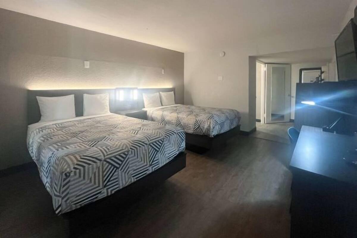 Hotellihuone, jossa on kaksi sänkyä, työpöytä ja televisio.