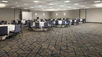 A conference room with rows of tables and chairs, a projector screen, and a podium.