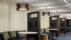A modern hotel lobby with a sectional sofa, round tables, and built-in TV screens. - Courtyard by Marriott Hartford Cromwell (Cromwell)