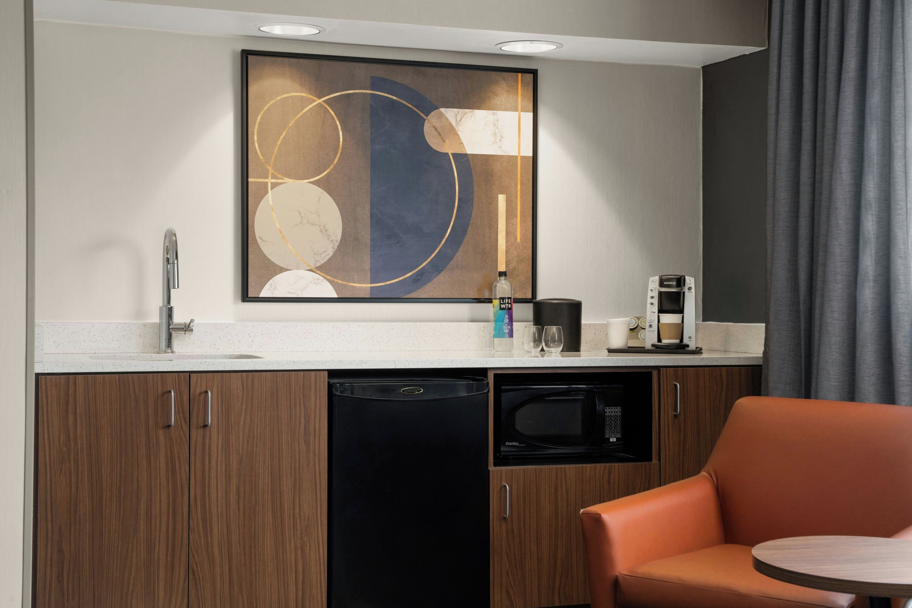 A compact kitchen with a dishwasher, a coffee maker, and a microwave.