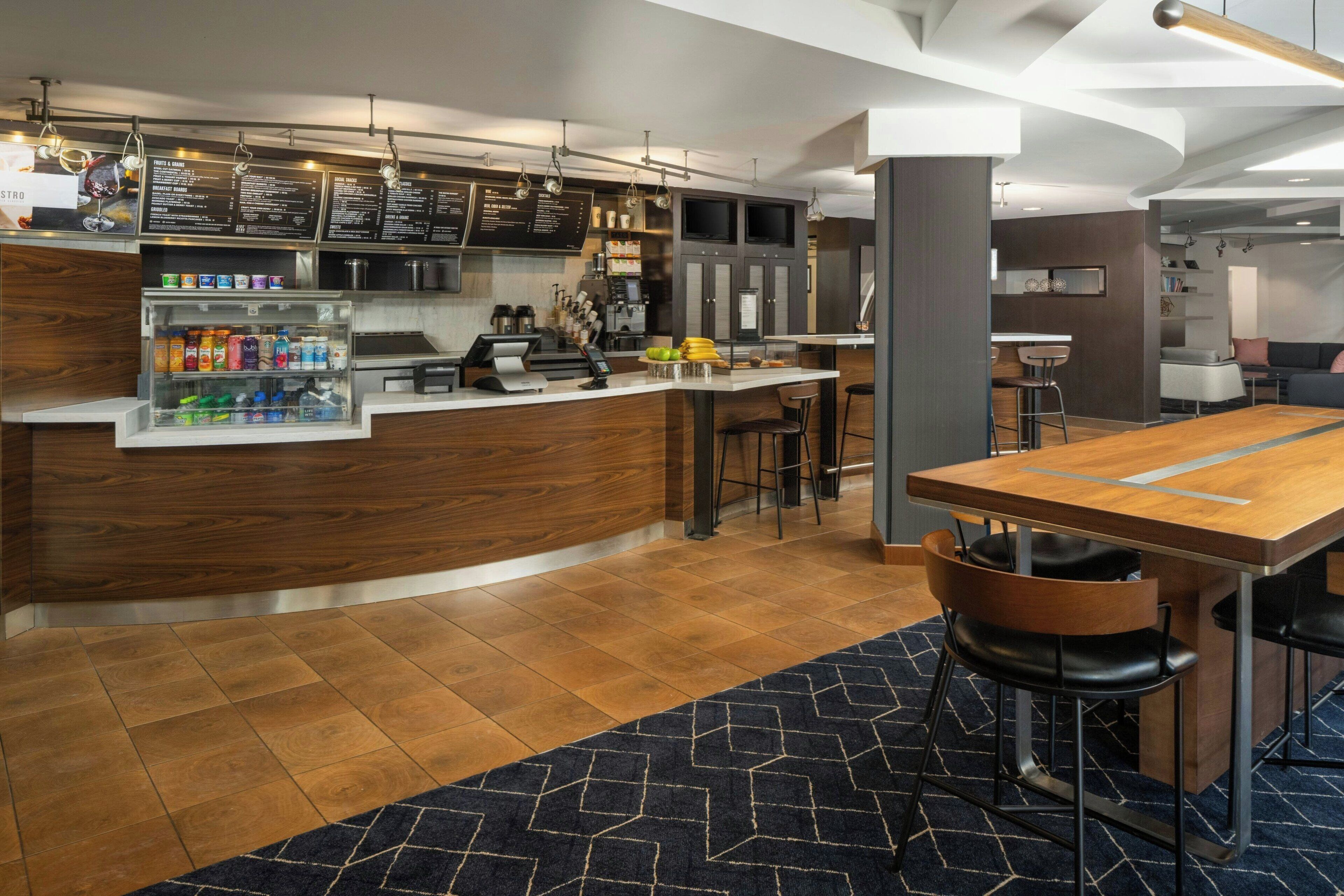 A modern kitchen area with a counter, bar stools, and a seating area with a table and chairs.