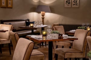 A dining area with a table set for two, surrounded by cushioned chairs.