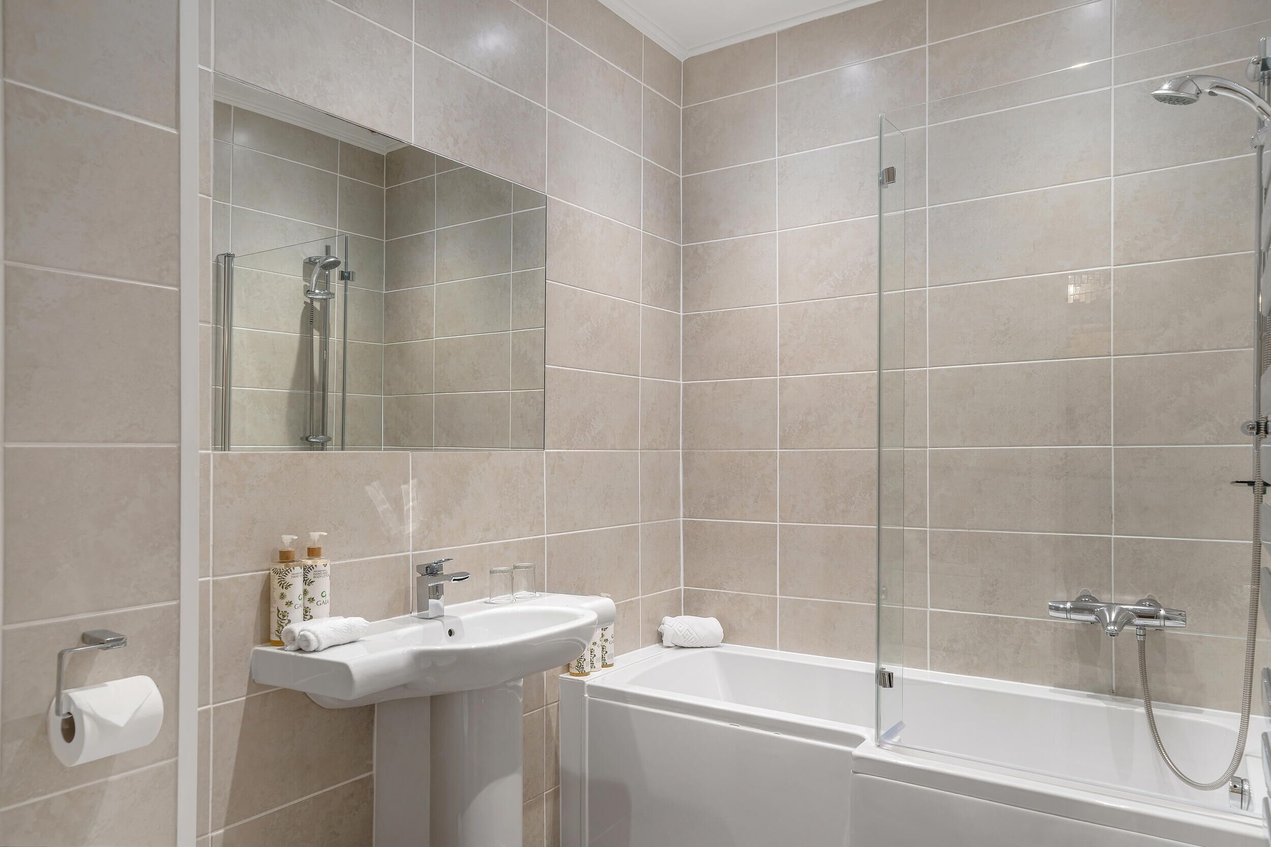 A modern bathroom with a glass-enclosed shower, a white sink, and a large mirror.