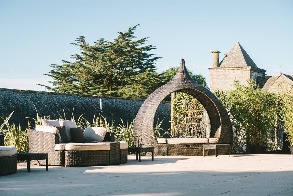 An outdoor seating area with wicker furniture and a distinctive arched structure.