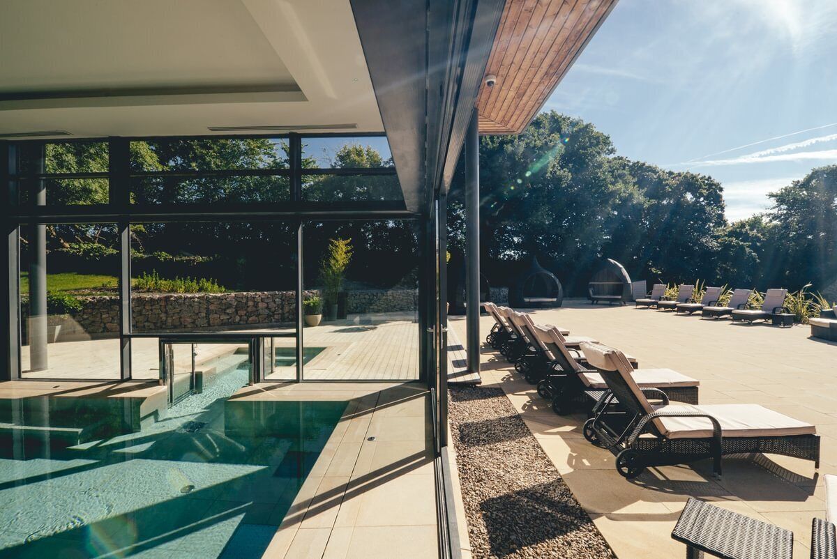 A modern outdoor pool area with lounge chairs and a clear view of the surrounding greenery.