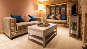 A cozy living room with a beige sofa, a white coffee table, and a stone fireplace. - Boringdon Hall Hotel and Spa (Plymouth)