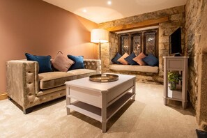 A cozy living room with a beige sofa, a white coffee table, and a stone fireplace. - Boringdon Hall Hotel and Spa (Plymouth)