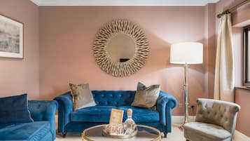A living room with a blue sofa, a grey armchair, a round coffee table, and a floor lamp.