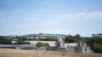 A stone building with a pitched roof, surrounded by a grassy field and trees.