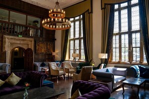 A spacious lounge with a fireplace, comfortable seating, and large windows with curtains. - Boringdon Hall Hotel and Spa (Plymouth)