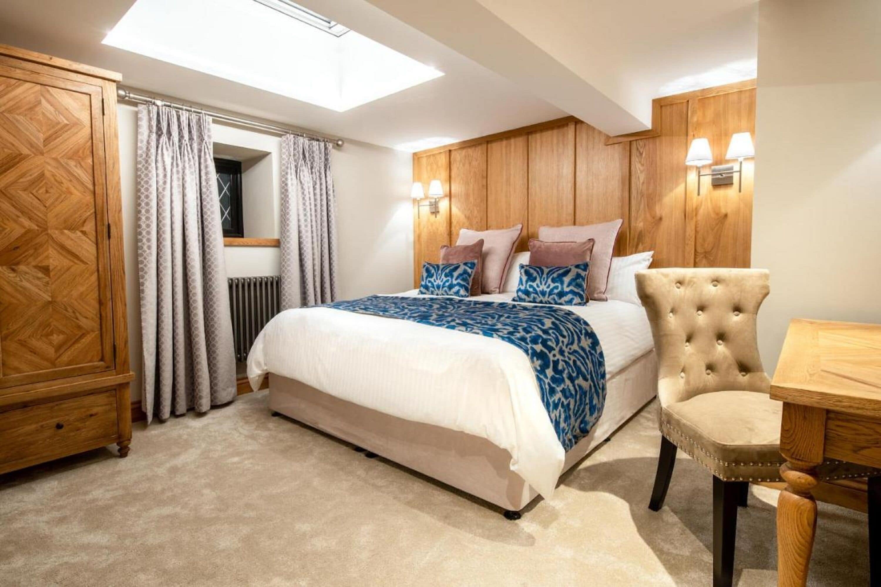 Un dormitorio con cama, armario de madera, silla y mesa.
