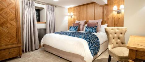Un dormitorio con cama, armario de madera, silla y mesa.