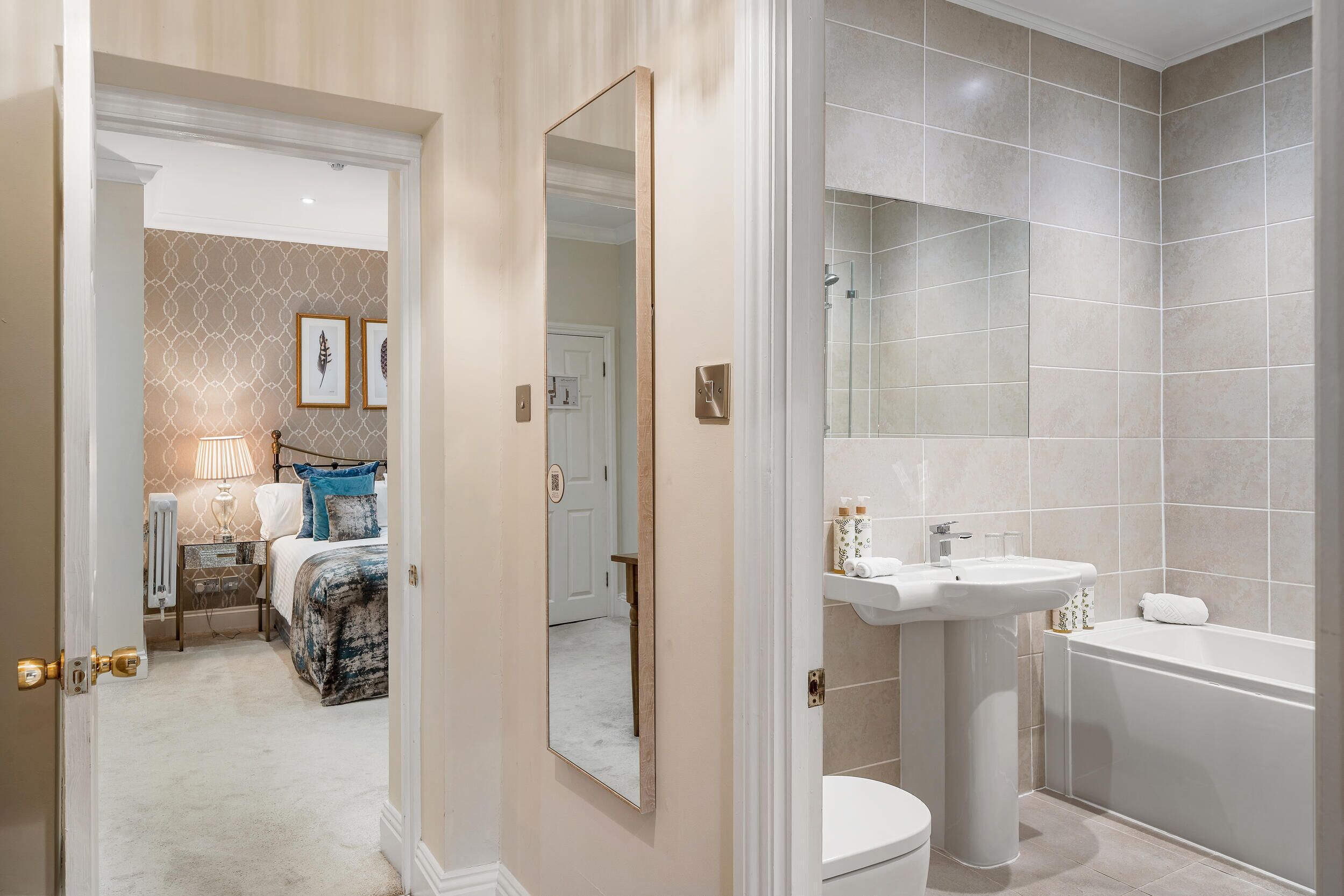 A modern bathroom with a bathtub, a pedestal sink, and a toilet.