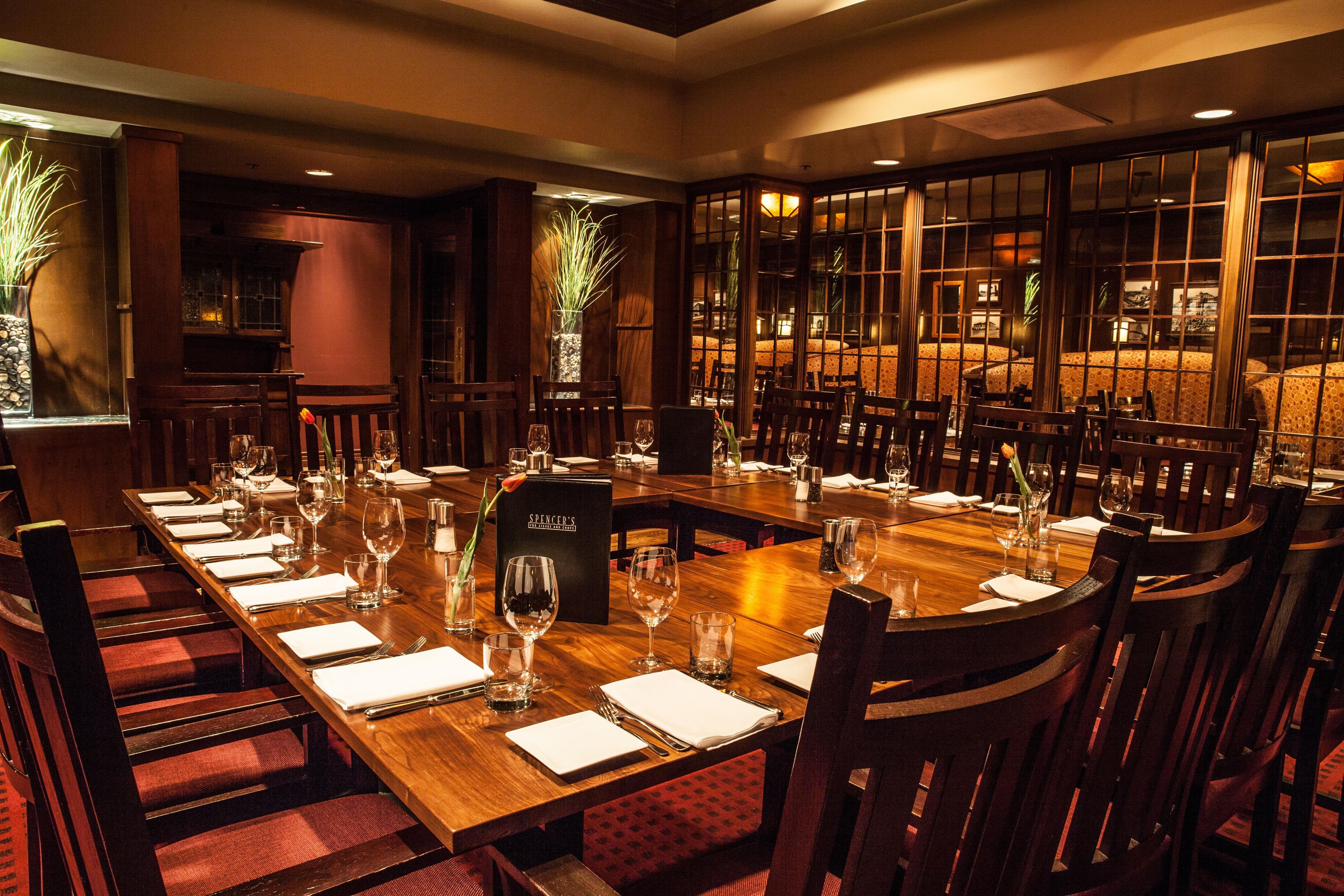 A restaurant with a long wooden table set for a meal, surrounded by chairs.