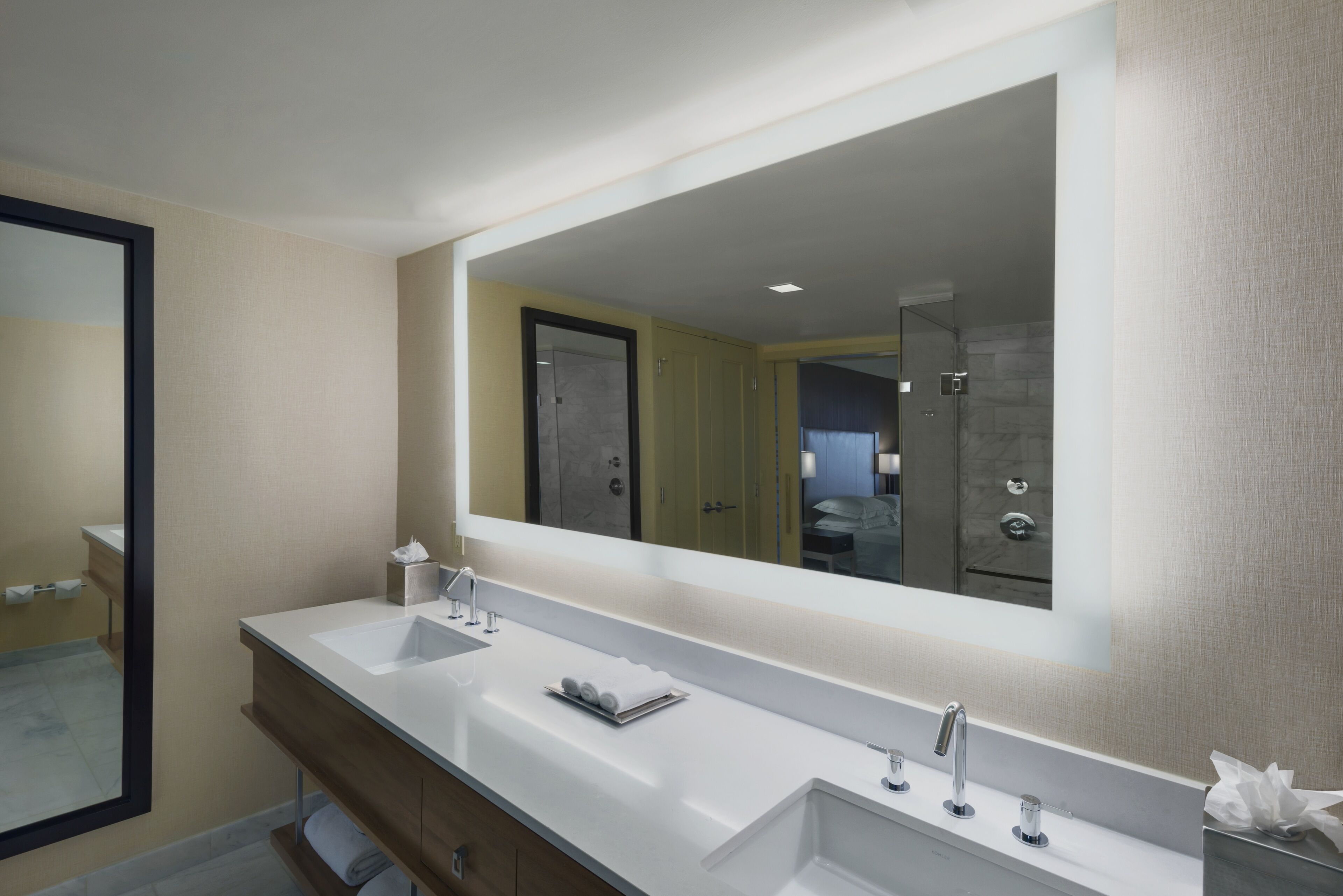 A modern bathroom with two sinks, a large mirror, and a shower area.
