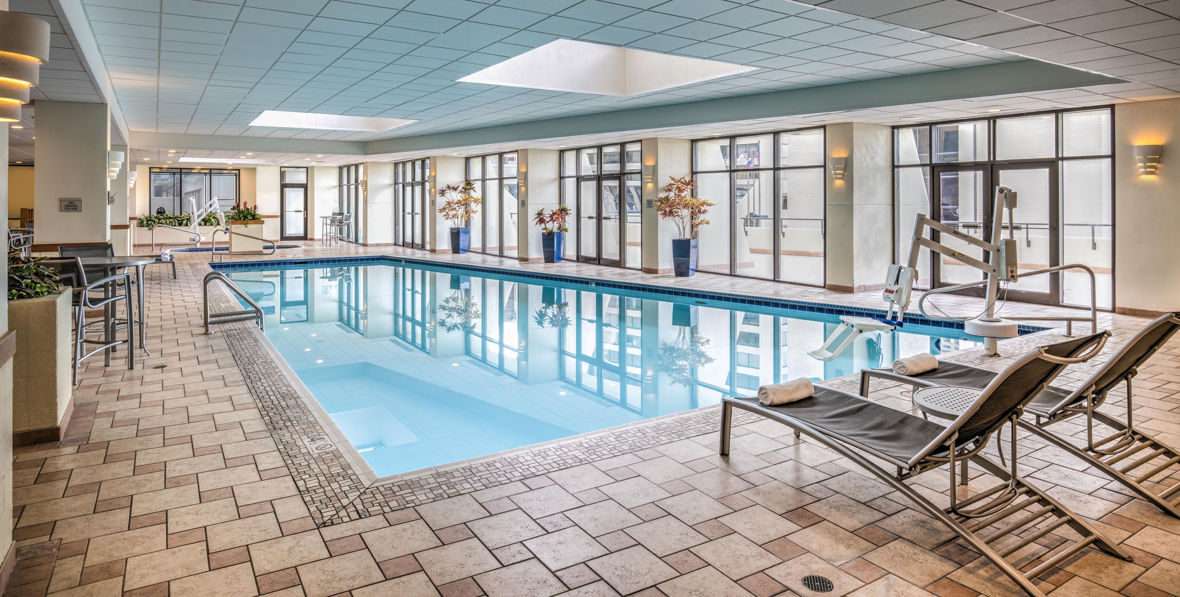 An indoor swimming pool with lounge chairs and potted plants.