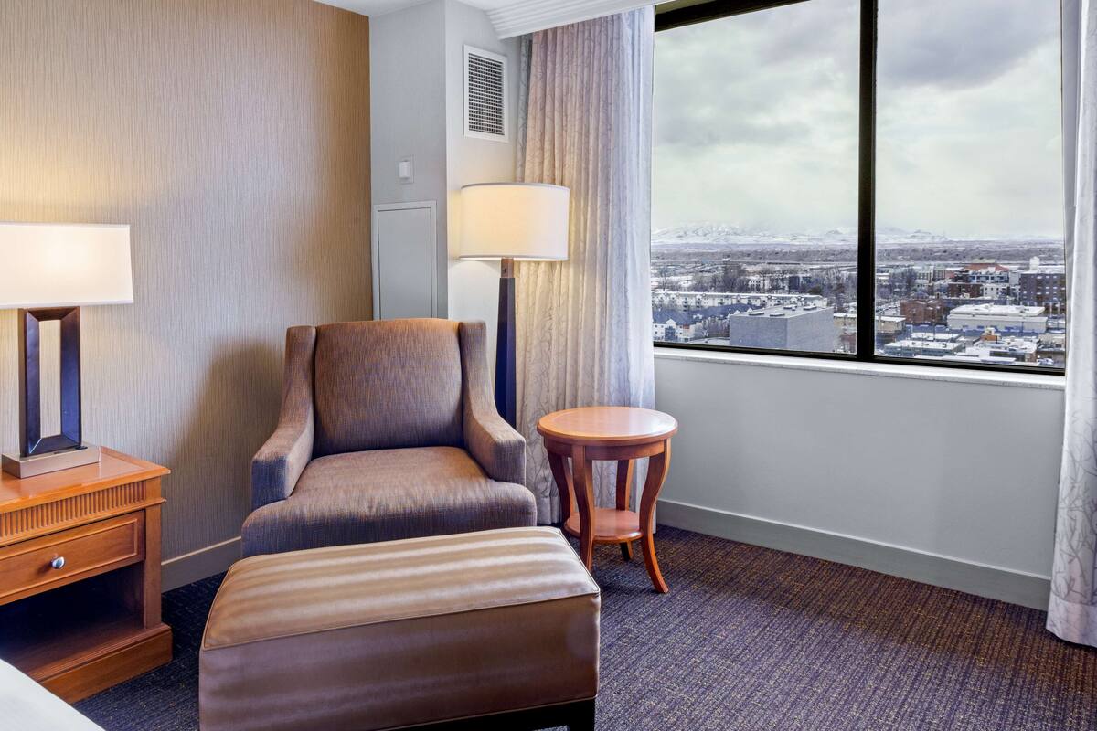 Une chambre d’hôtel avec vue sur la ville, un canapé, une petite table et une lampe.