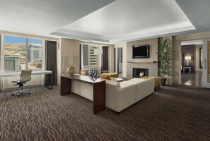 Ein Hotelzimmer mit einem großen Bett, einem Schreibtisch, einem Sessel, einem Fernseher, einem Kamin und Blick auf die Stadt.