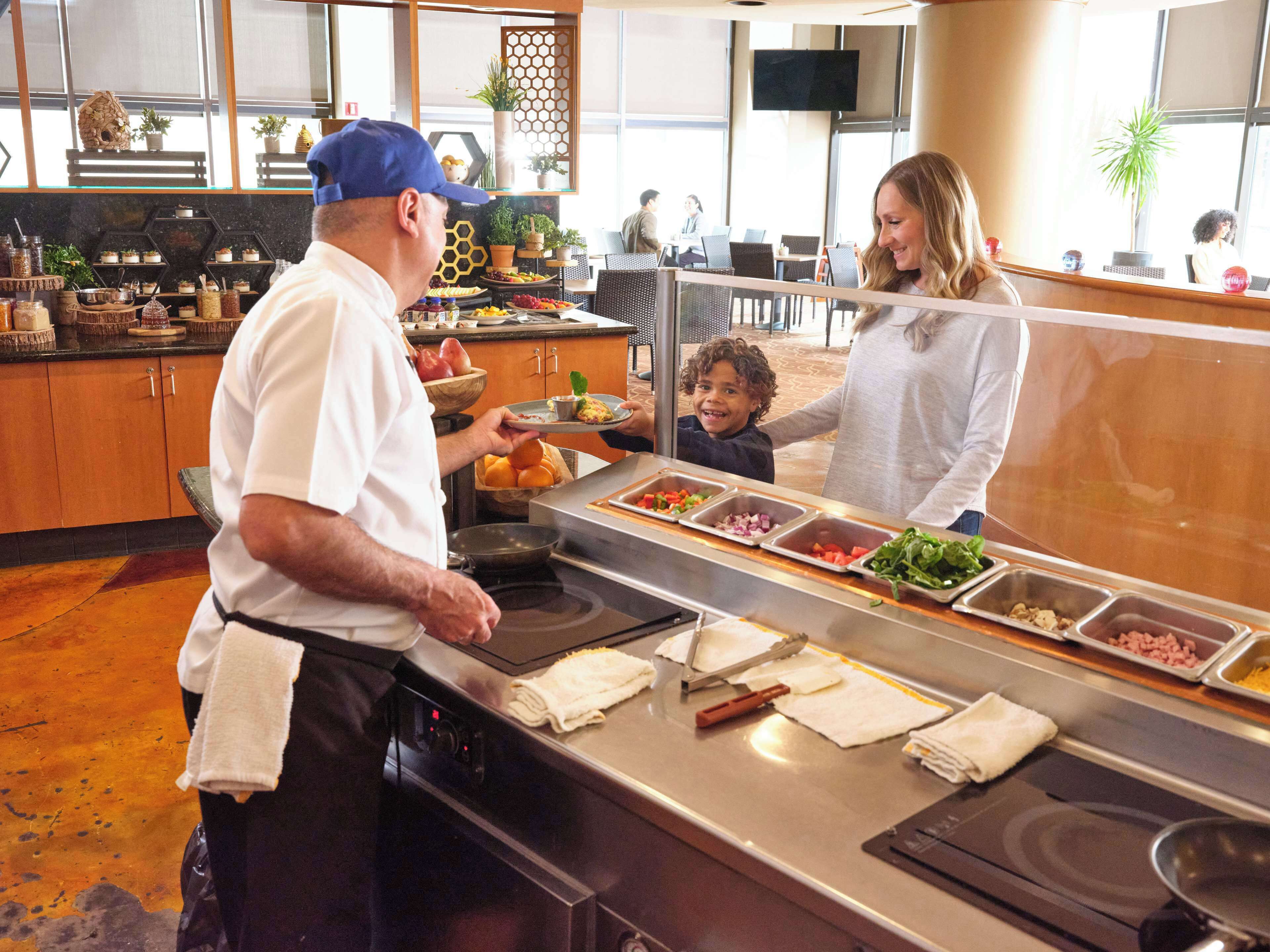 A buffet area with a variety of food options, a counter with a chef, and a seating area with tables and chairs.