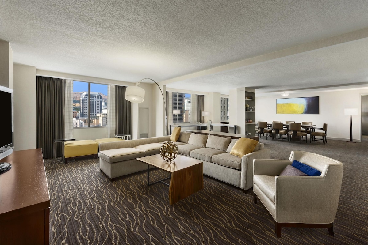 Une chambre d’hôtel comprenant un espace salon, un coin repas et offrant une vue sur le paysage urbain.