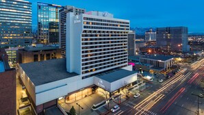 A multi-story hotel with a modern design, featuring a prominent Hilton logo, a large glass facade, and a flat roof.