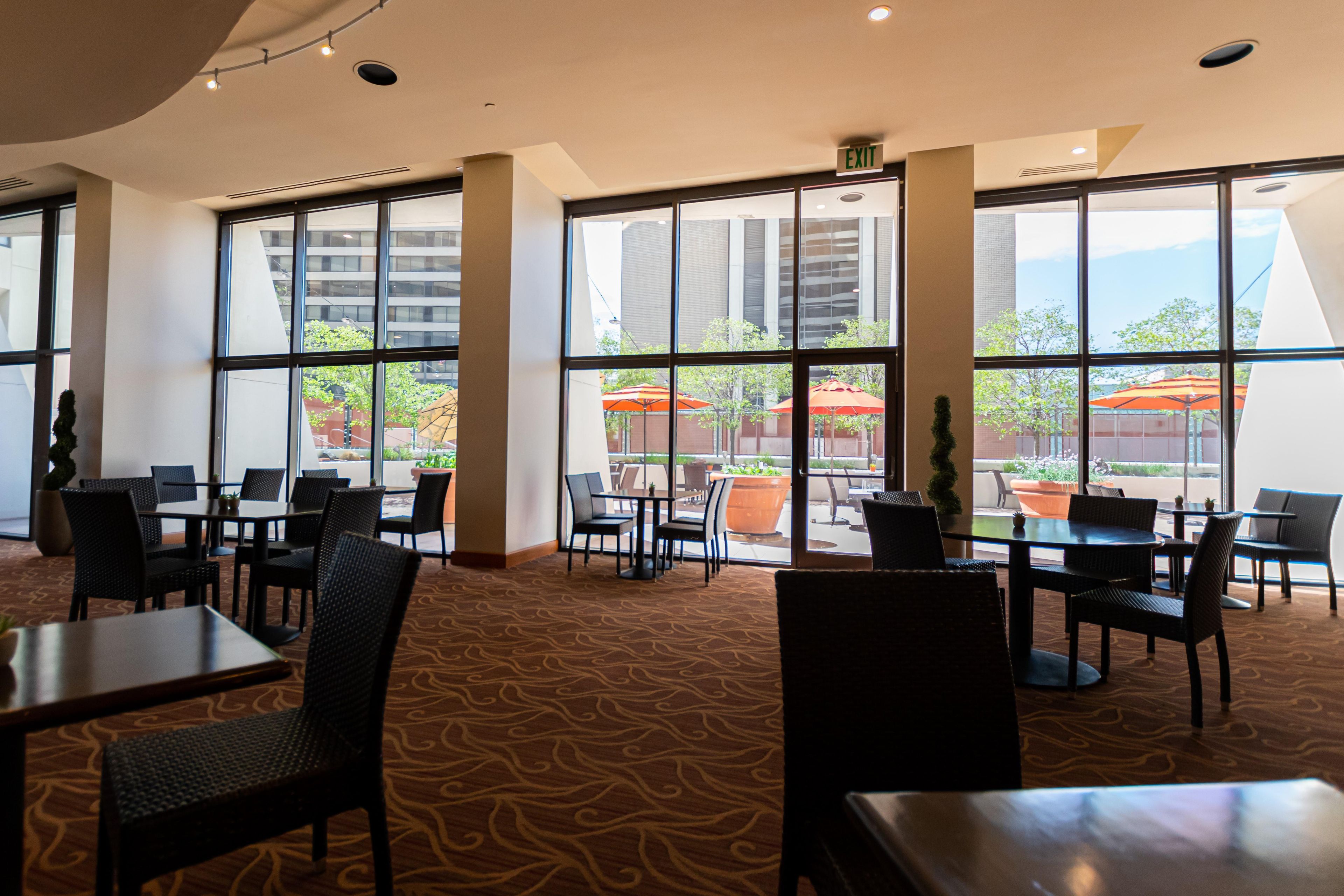 A hotel lobby with large windows, multiple seating areas, and a carpeted floor.
