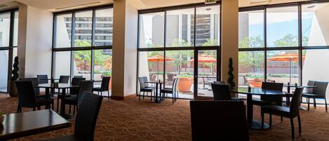 A hotel lobby with large windows, multiple seating areas, and a carpeted floor.