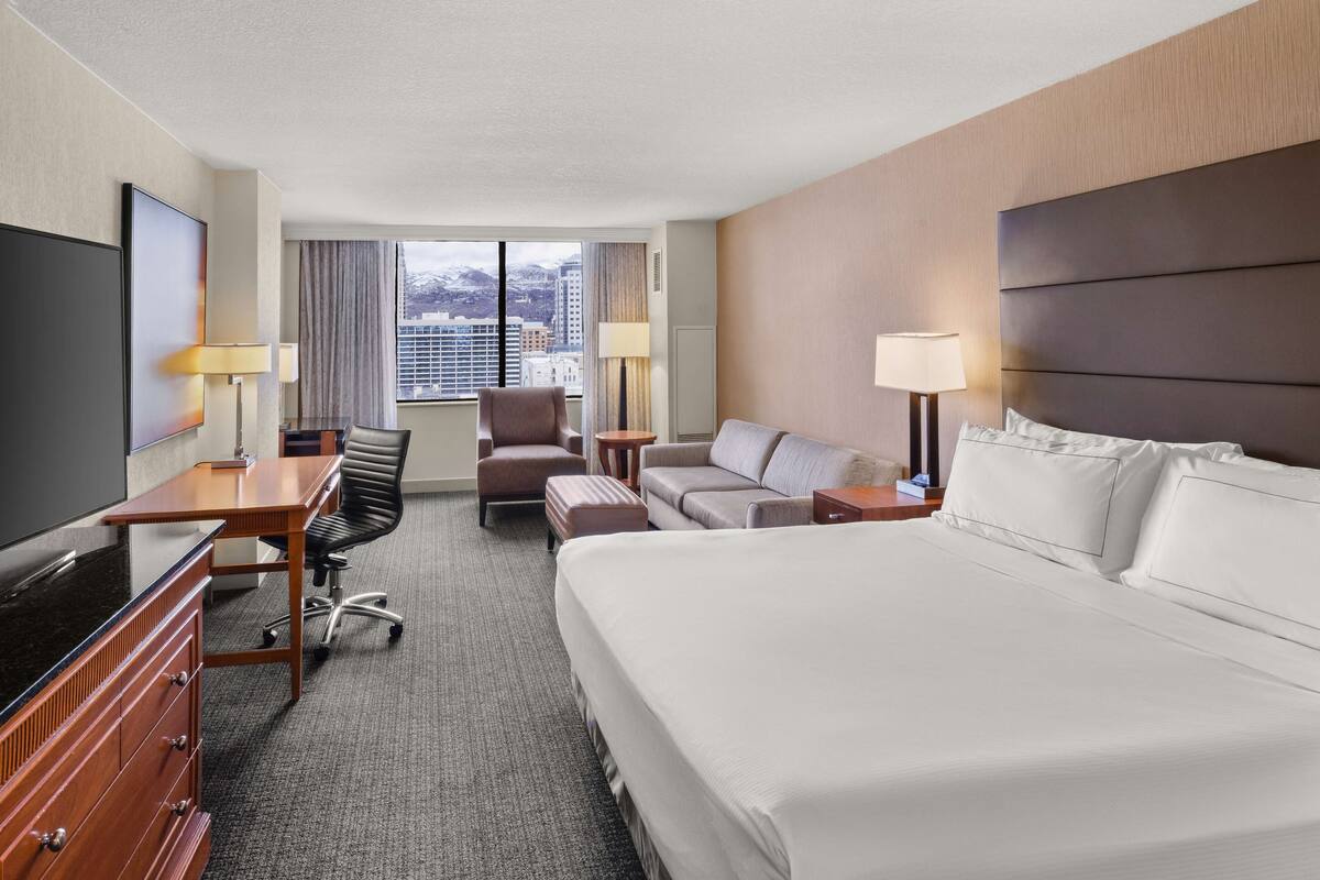 Une chambre d’hôtel avec un grand lit, un bureau avec une chaise, un canapé et une télévision.
