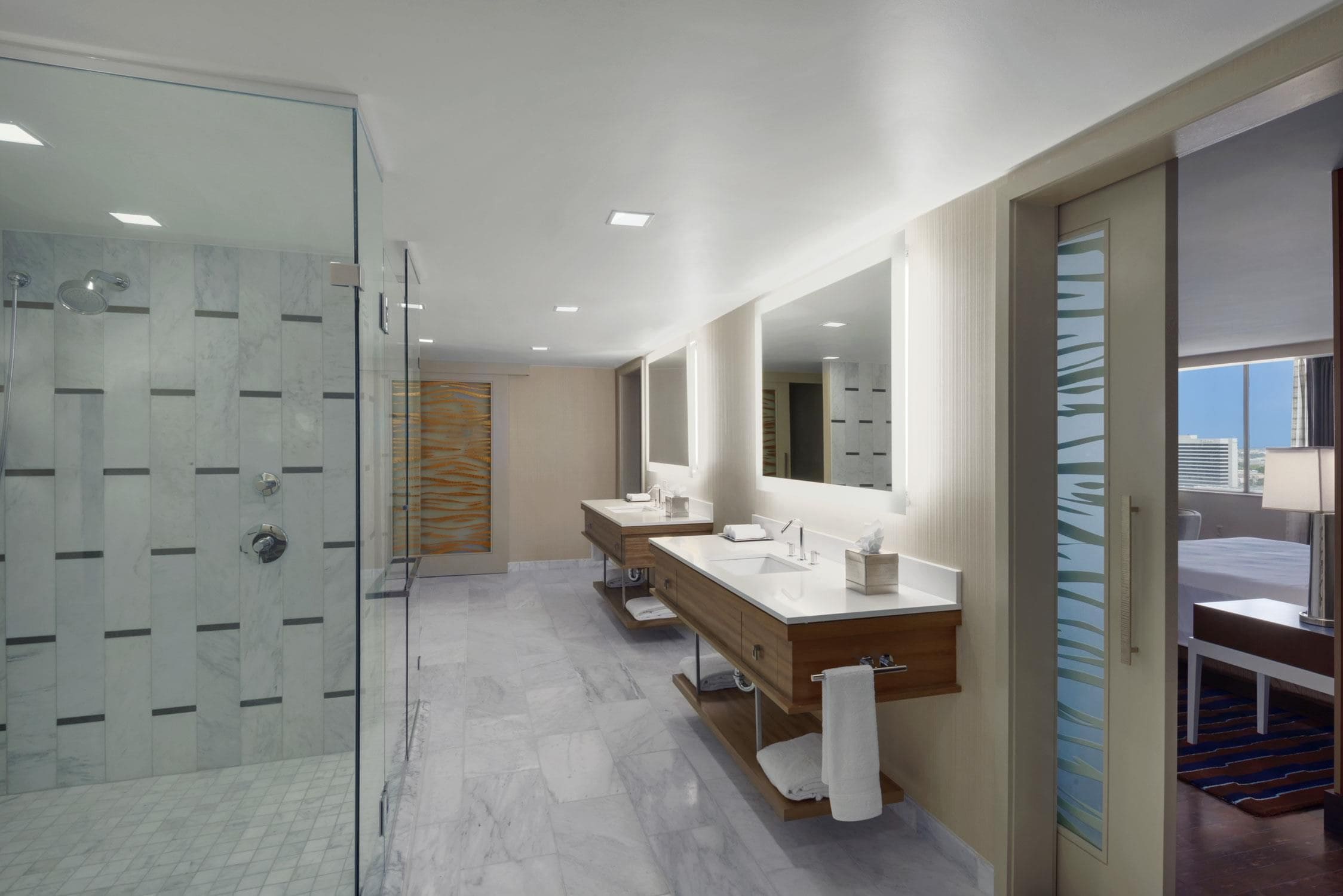 A modern bathroom with a glass shower enclosure, a large mirror, and a wooden vanity with a sink.