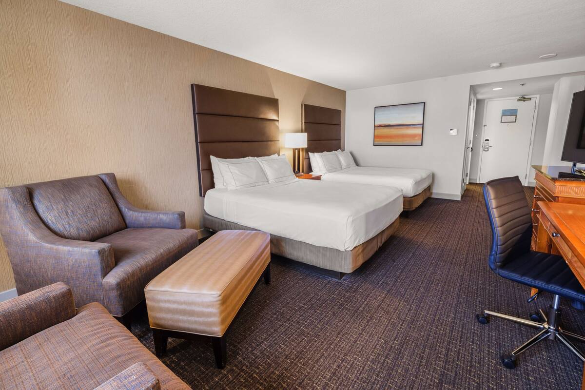 Une chambre d’hôtel avec deux lits, un bureau, une chaise et un canapé.