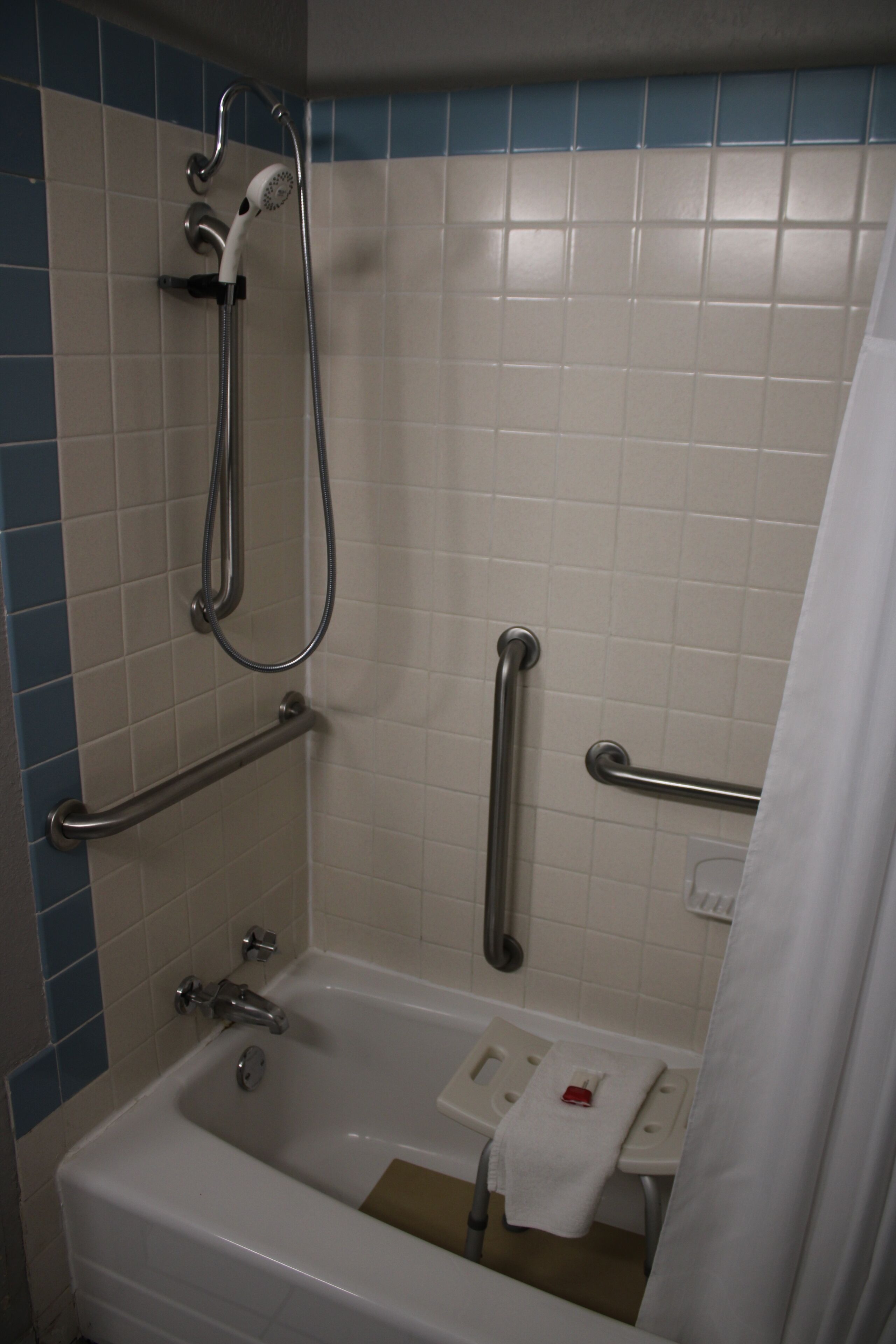 A bathroom with a bathtub, grab bars, and a shower head.