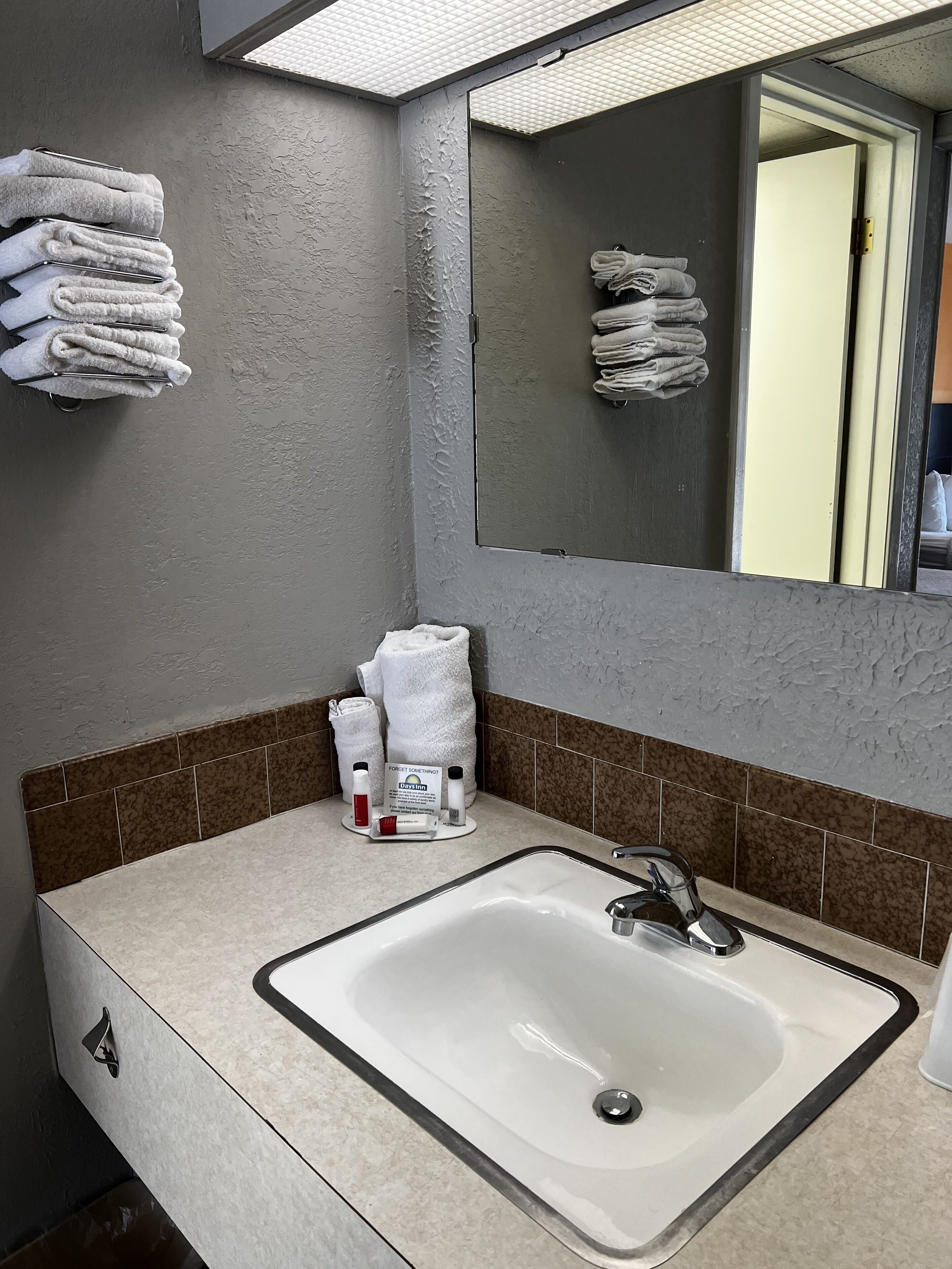 Un baño con un espejo grande, un lavamanos y toallas en un tendedero.