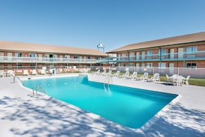 Una piscina al aire libre de temporada, sillones reclinables de piscina