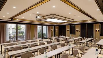 A conference room with long tables, chairs, and a ceiling with recessed lighting and a central light fixture.