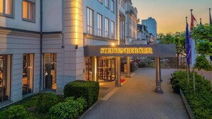 A hotel entrance with a sign reading 'STEIGENBERGER,' a paved pathway, and a well-maintained hedge. - Steigenberger Hotel Bad Homburg (Bad Homburg v.d. Hoehe)