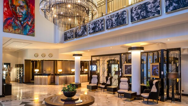 A spacious lobby with a chandelier, seating area, reception desk, and artwork on the walls. - Steigenberger Hotel Bad Homburg (Bad Homburg v.d. Hoehe)