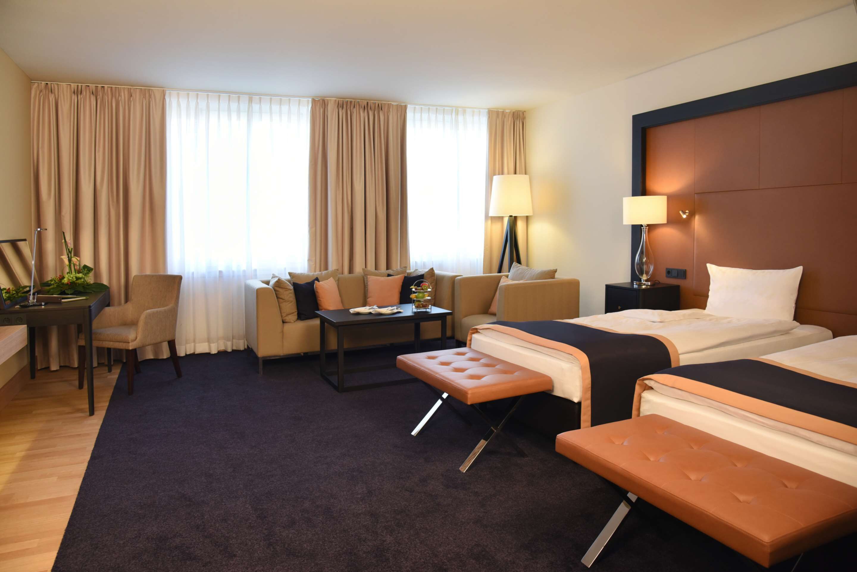 Habitación de hotel con dos camas, un sofá, una mesa de centro y un escritorio.