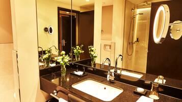 A modern bathroom with a large mirror, dual sinks, and a shower area.