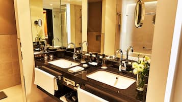 A modern bathroom with two sinks, a large mirror, and a shower area.