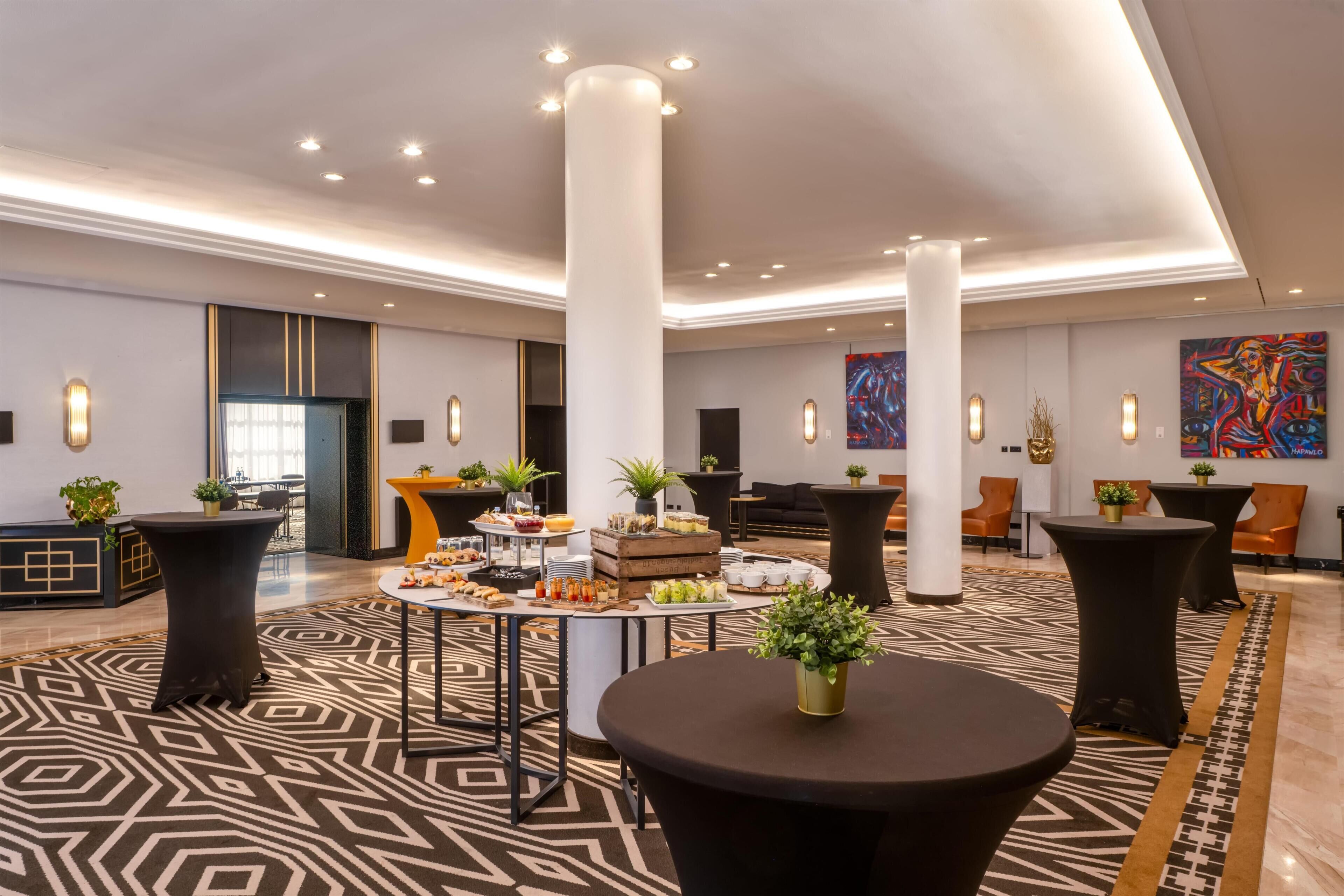 Un hall d’entrée spacieux avec de hauts plafonds, un éclairage moderne et un espace buffet central.