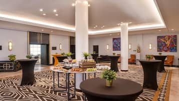 Un hall d’entrée spacieux avec de hauts plafonds, un éclairage moderne et un espace buffet central.