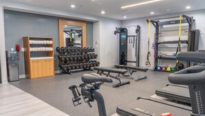 A gym with treadmills, weight benches, and a squat rack. - voco Orange County - Airport by IHG (Santa Ana)