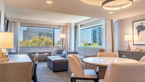 A modern hotel room with a dining area, seating, and large windows offering a city view. - voco Orange County - Airport by IHG (Santa Ana)