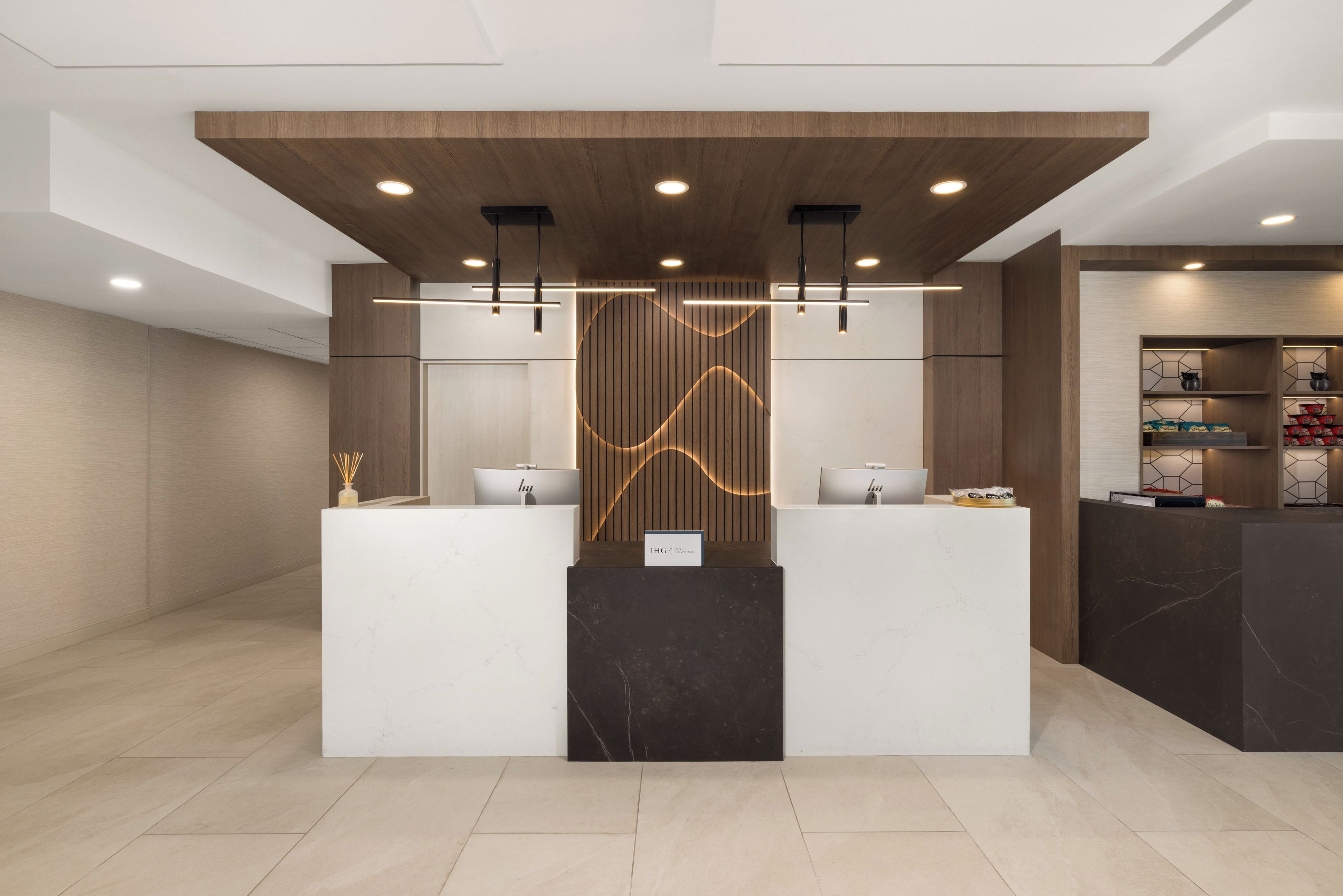 A reception area with two reception desks, a wooden accent wall, and a modern light fixture.