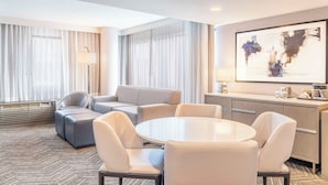 A modern hotel room with a sofa set, a dining table, and a kitchen area. - voco Orange County - Airport by IHG (Santa Ana)