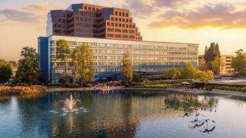 A modern hotel with a large building, a reflecting pool, and a fountain.